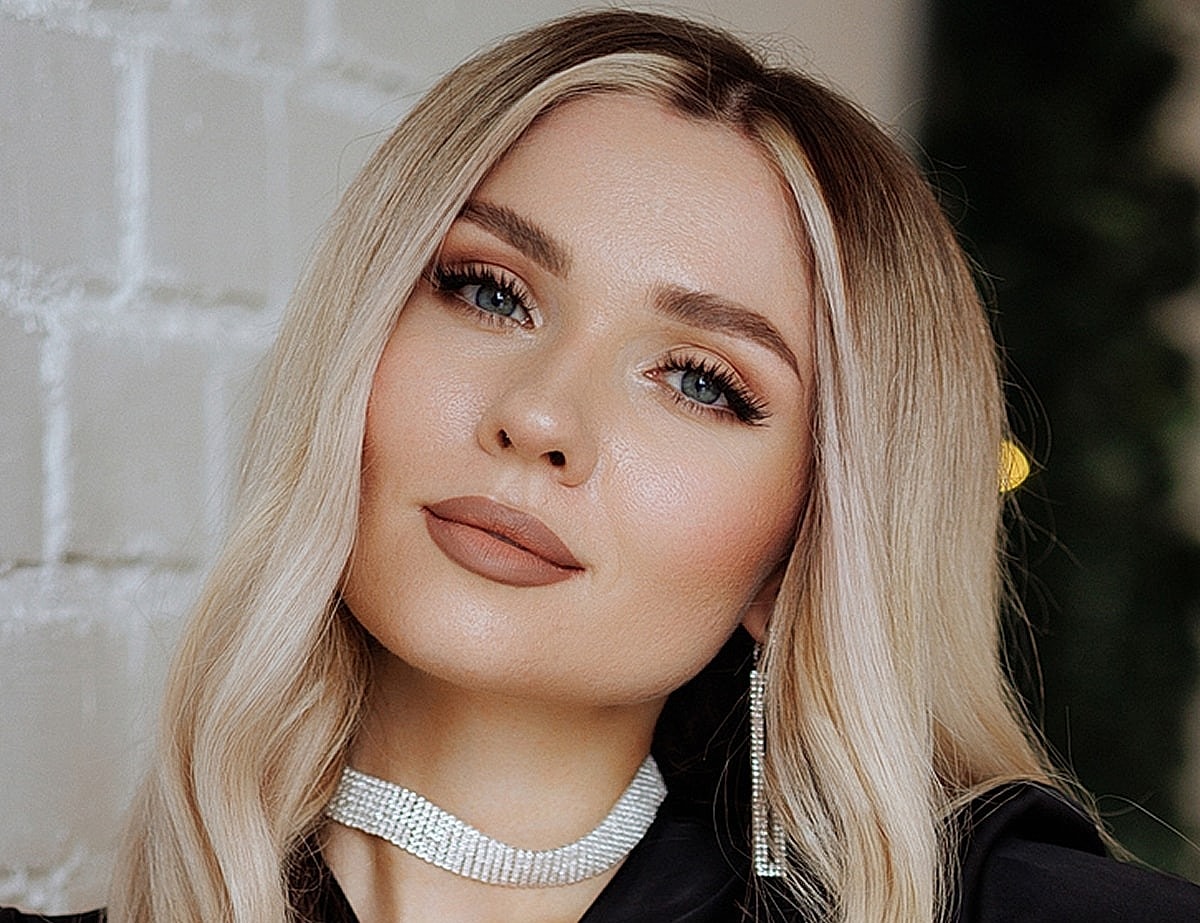 Blonde woman with elegant makeup and accessories.