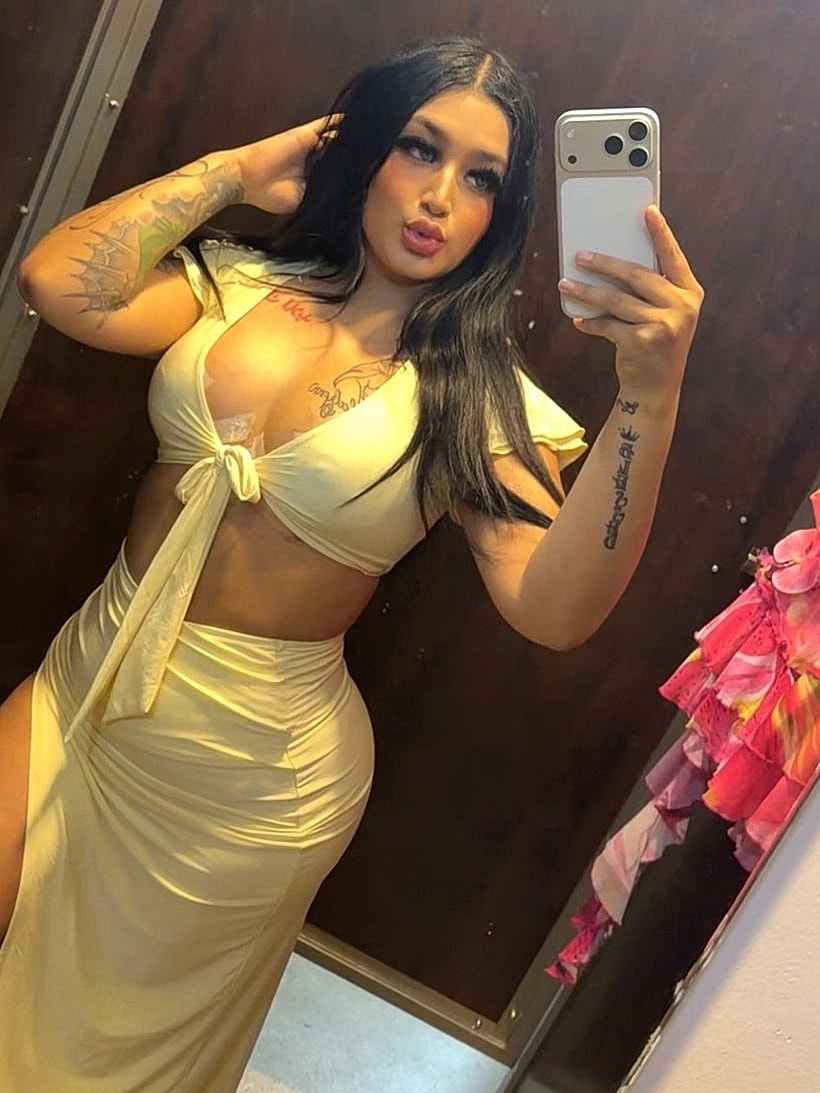 Houston plastic surgery patient posing in mirror wearing stylish outfit.