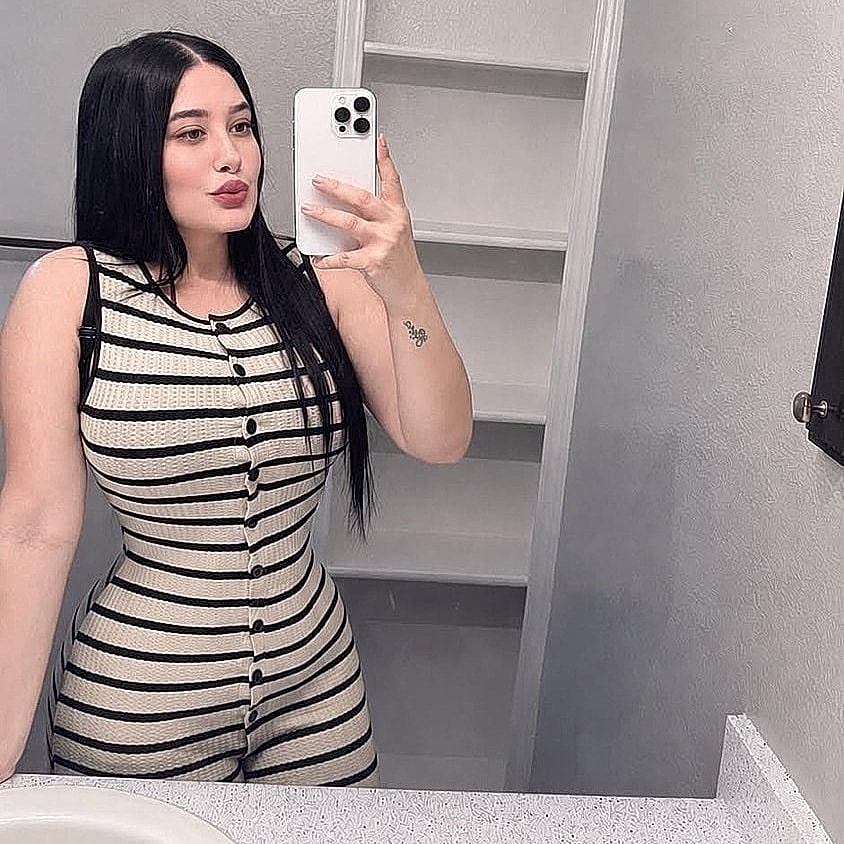 Houston plastic surgery patient posing in mirror wearing striped outfit.