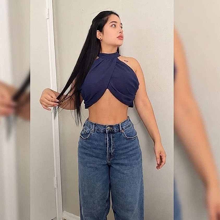 Houston plastic surgery patient posing in fashionable crop top and jeans.