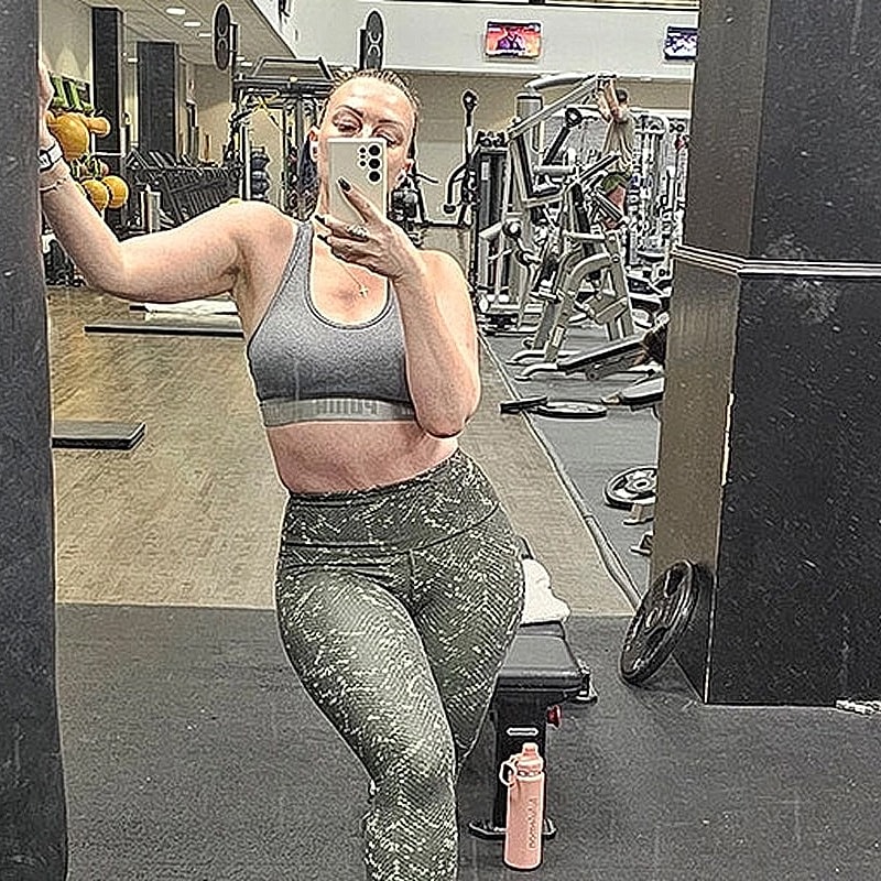 Houston plastic surgery patient taking mirror selfie in gym outfit.