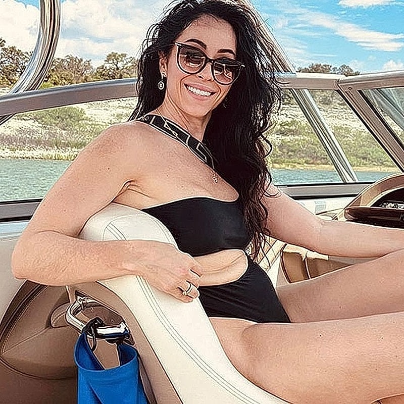 Houston plastic surgery patient in black swimsuit on a boat.