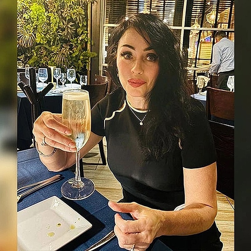 Houston plastic surgery patient toasting with champagne in restaurant setting.