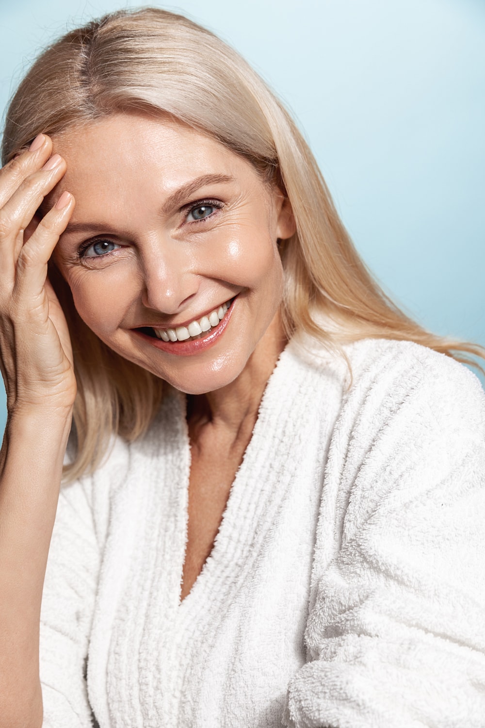 Smiling woman in a white robe, serene expression.